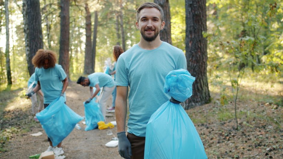 Group of volunteers picking up litter in a forest to promote environmental awareness.